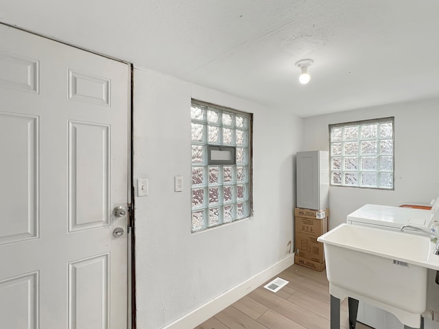 laundry area with washing machine and dryer, sink, and light wood-type flooring