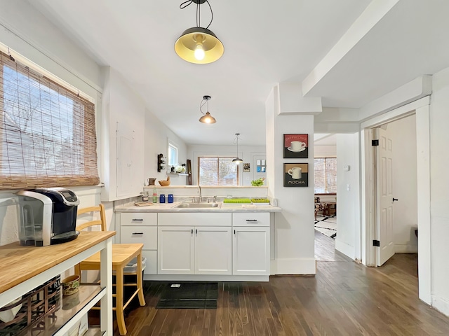 kitchen with dark hardwood / wood-style floors, decorative light fixtures, sink, and white cabinets