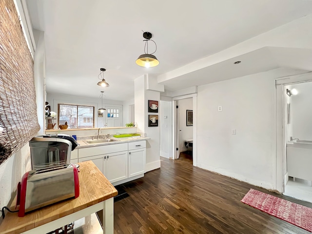 kitchen featuring hanging light fixtures, sink, white cabinets, and dark hardwood / wood-style flooring