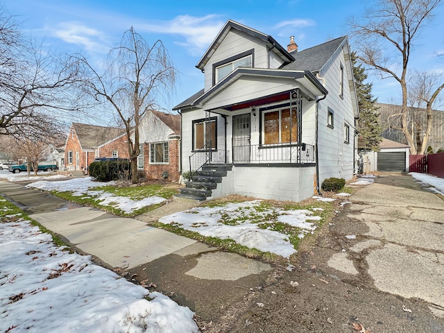 bungalow-style home with a garage, an outdoor structure, and a porch