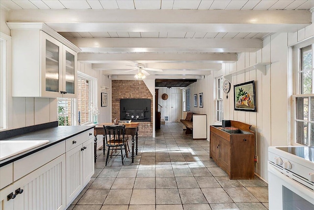 kitchen featuring ceiling fan, white electric stove, beam ceiling, and white cabinets