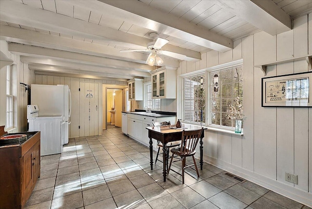 kitchen featuring light tile patterned flooring, white cabinetry, washer / dryer, ceiling fan, and beam ceiling