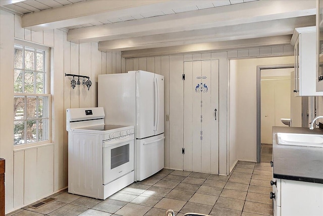 kitchen with sink, white cabinetry, wooden walls, beamed ceiling, and white appliances