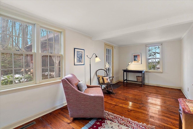 sitting room with beam ceiling, dark wood-type flooring, and ornamental molding