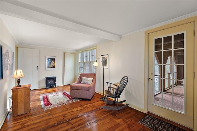 sitting room with beam ceiling, wood-type flooring, ornamental molding, and a wood stove