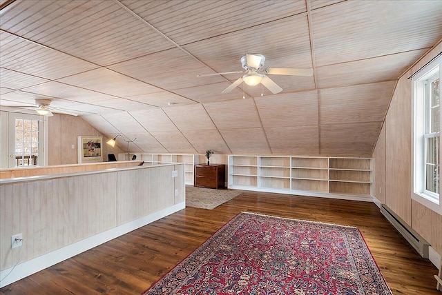 additional living space with lofted ceiling, a baseboard heating unit, dark hardwood / wood-style flooring, built in shelves, and wood walls