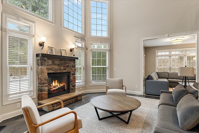 living room featuring a fireplace, dark hardwood / wood-style flooring, and a towering ceiling