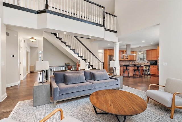 living room featuring a towering ceiling, dark hardwood / wood-style floors, and ornate columns