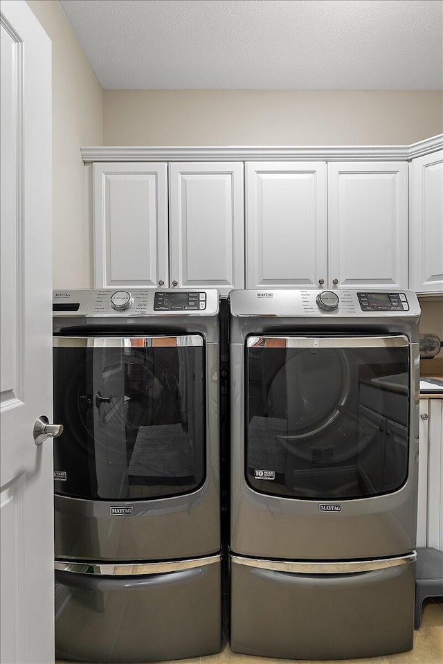 laundry room featuring cabinets and washer and dryer