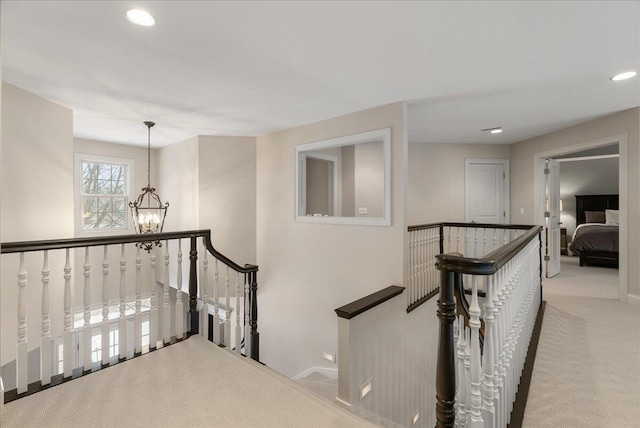 hall featuring an inviting chandelier and light colored carpet