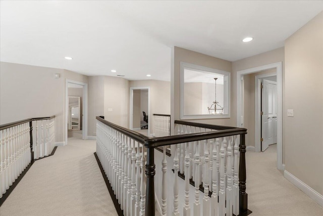 corridor with light colored carpet and a chandelier