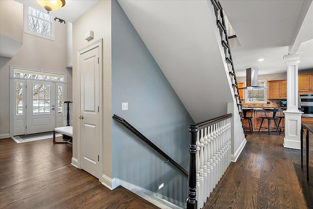 stairway featuring ornate columns and wood-type flooring