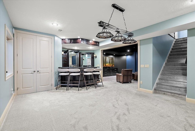 kitchen with pendant lighting, a breakfast bar area, light carpet, and a textured ceiling