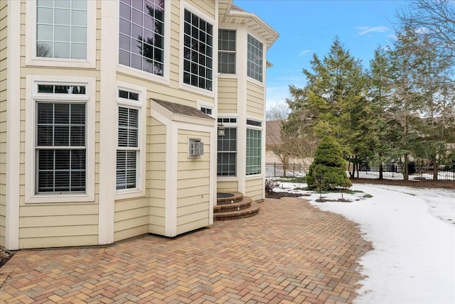 snow covered property entrance with a patio