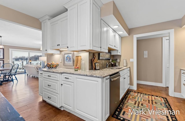 kitchen featuring hardwood / wood-style floors, white cabinetry, dishwasher, sink, and light stone countertops