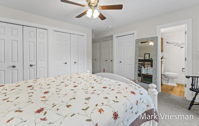 bedroom with connected bathroom, two closets, hardwood / wood-style floors, and ceiling fan