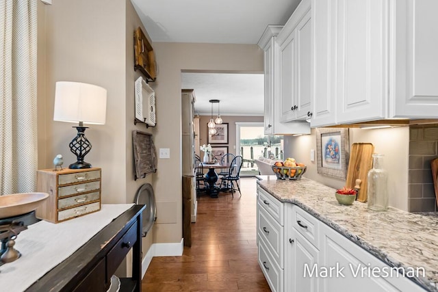 kitchen featuring white cabinetry, decorative light fixtures, dark hardwood / wood-style flooring, light stone countertops, and decorative backsplash