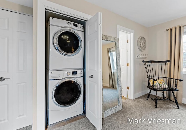 washroom with stacked washer / drying machine and carpet