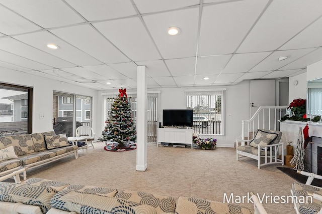 living room featuring plenty of natural light, carpet flooring, and a drop ceiling