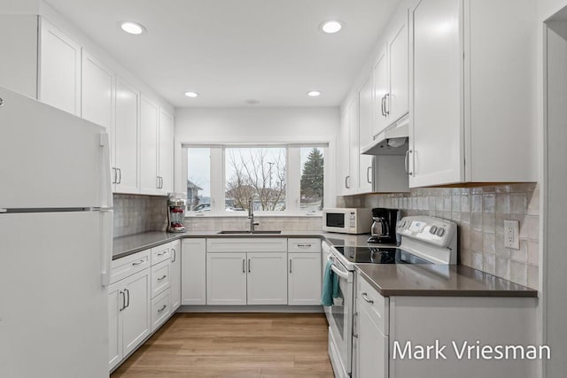 kitchen featuring sink, white appliances, white cabinetry, light hardwood / wood-style floors, and decorative backsplash