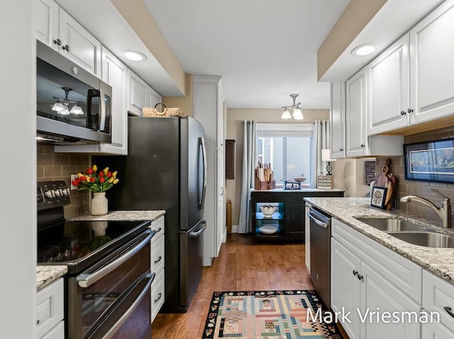 kitchen featuring sink, dark wood-type flooring, stainless steel appliances, light stone counters, and white cabinets