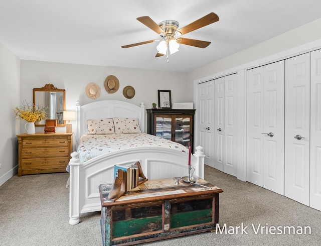 carpeted bedroom featuring multiple closets and ceiling fan