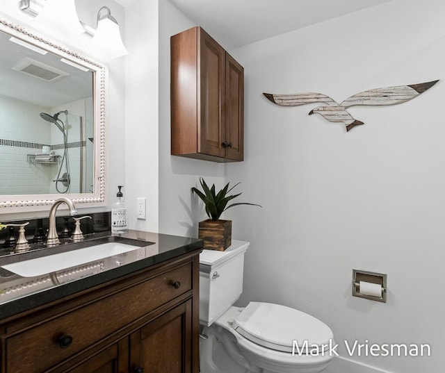 bathroom featuring vanity, toilet, and a tile shower