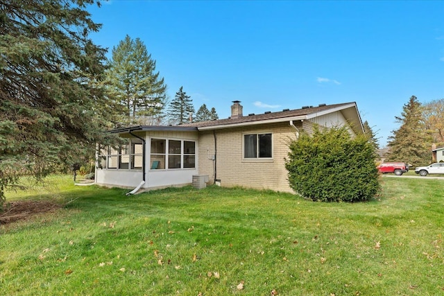 back of house featuring a lawn and a sunroom