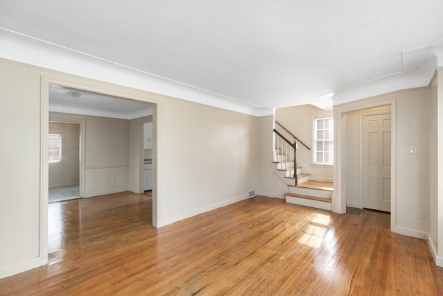 unfurnished living room featuring ornamental molding and light hardwood / wood-style flooring