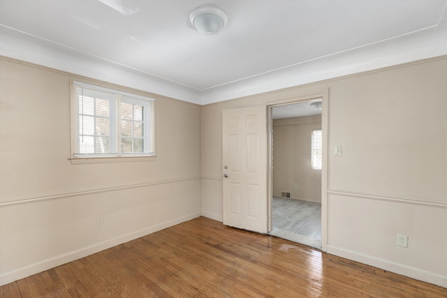 unfurnished bedroom with hardwood / wood-style flooring and multiple windows