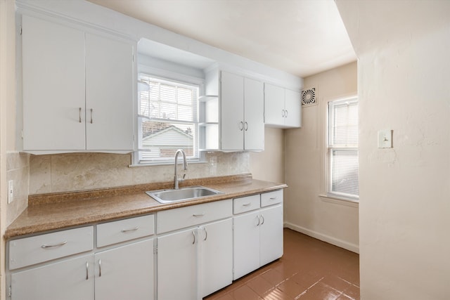 kitchen featuring white cabinetry, sink, and tasteful backsplash