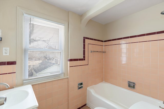 bathroom featuring vanity, toilet, a bathing tub, and tile walls