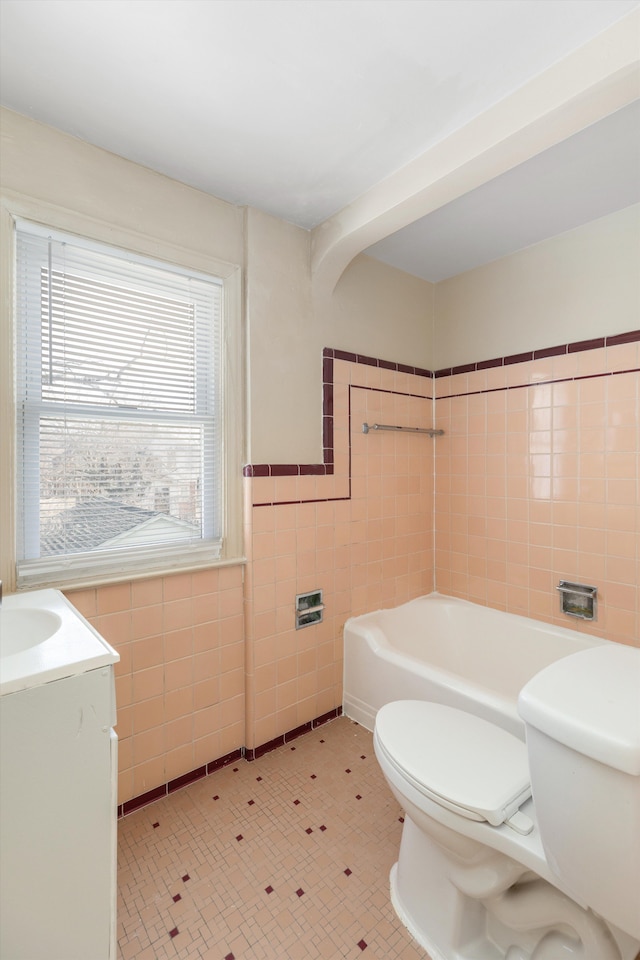 bathroom with vanity, toilet, tile walls, and a washtub