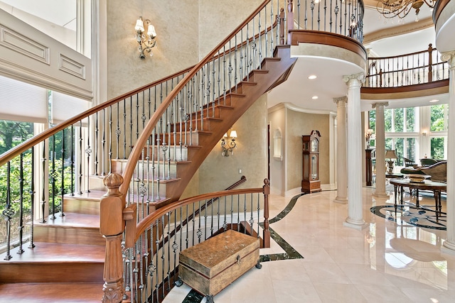 staircase featuring a towering ceiling and decorative columns