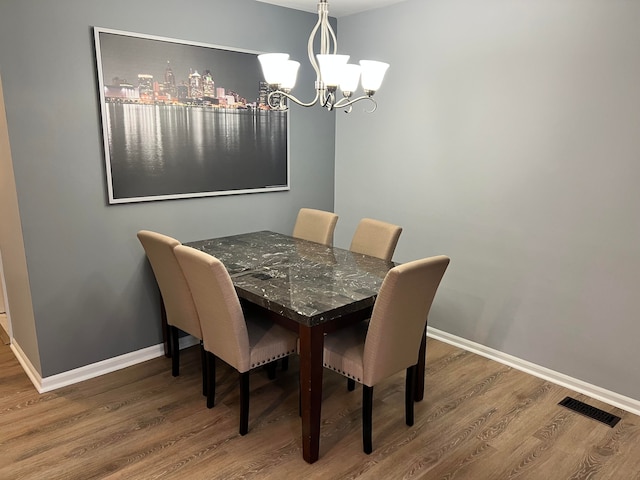 dining space featuring wood-type flooring and a chandelier