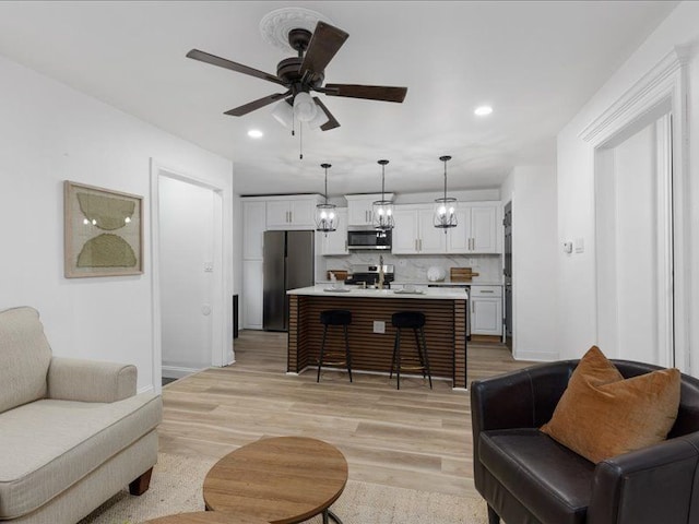 living room with light hardwood / wood-style flooring and ceiling fan