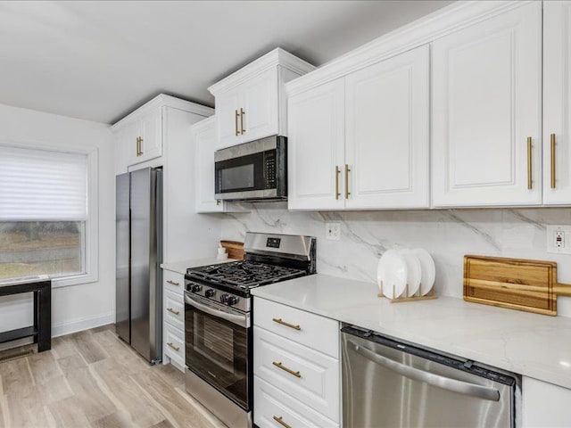 kitchen with backsplash, stainless steel appliances, light stone countertops, and white cabinets