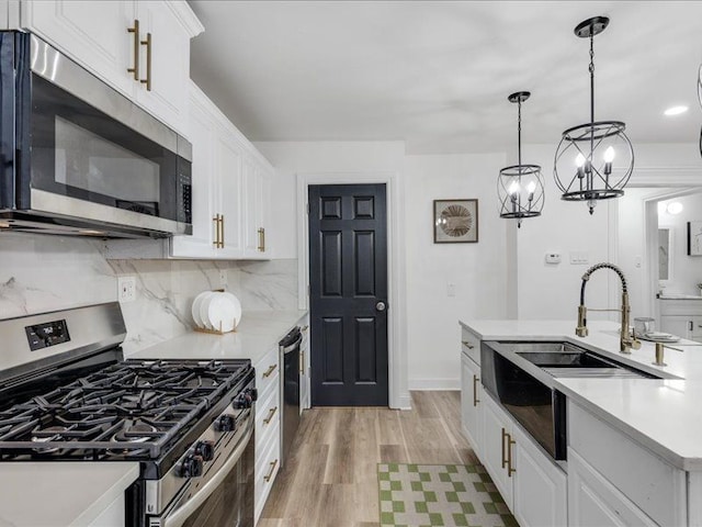 kitchen with white cabinetry, sink, pendant lighting, and stainless steel appliances