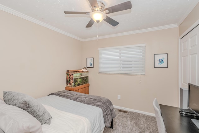 carpeted bedroom featuring a textured ceiling, ornamental molding, a closet, and ceiling fan