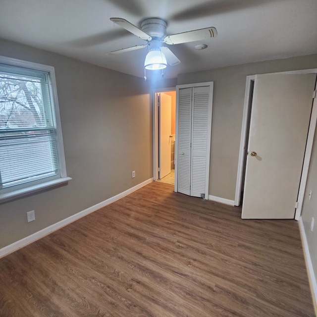 unfurnished bedroom with two closets, ceiling fan, and hardwood / wood-style flooring