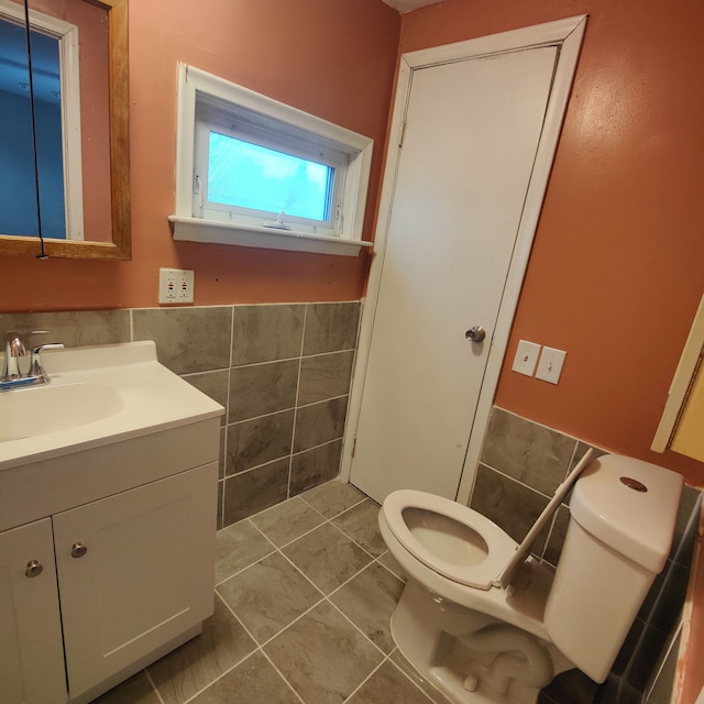 bathroom with tile walls, vanity, tile patterned flooring, and toilet