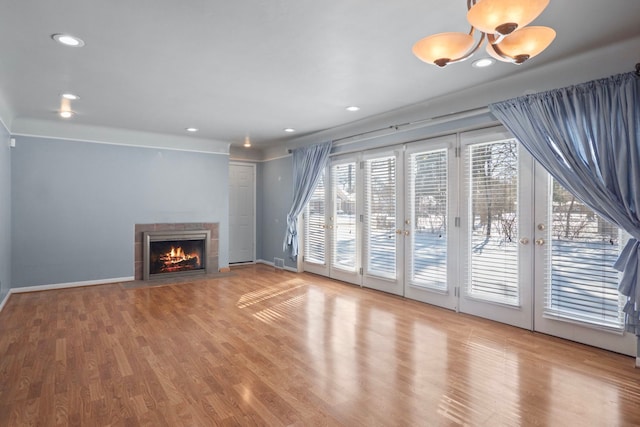 unfurnished living room featuring recessed lighting, baseboards, wood finished floors, and a tile fireplace