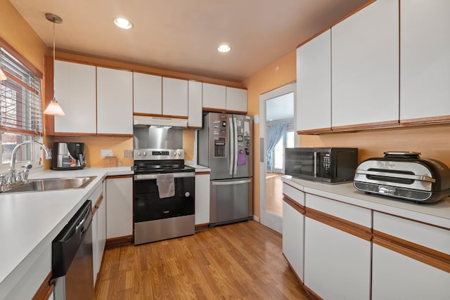 kitchen featuring under cabinet range hood, appliances with stainless steel finishes, hanging light fixtures, and white cabinets