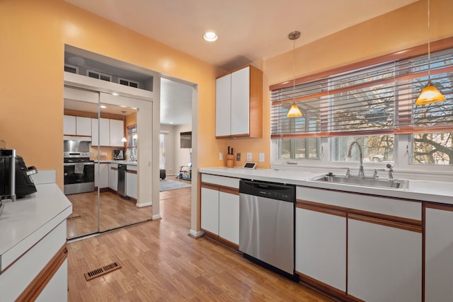 kitchen featuring hanging light fixtures, white cabinetry, appliances with stainless steel finishes, and light countertops