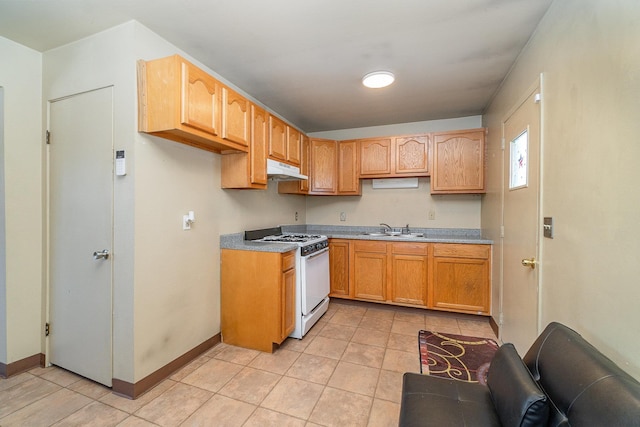 kitchen featuring white gas range, sink, and light tile patterned floors