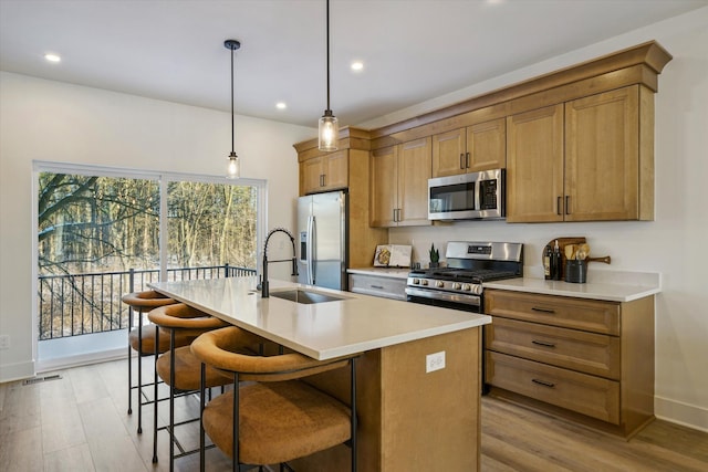 kitchen with pendant lighting, an island with sink, sink, a kitchen breakfast bar, and stainless steel appliances