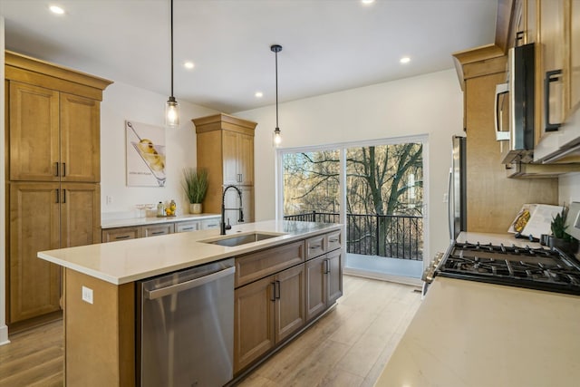 kitchen featuring light wood-type flooring, dishwasher, an island with sink, and a sink