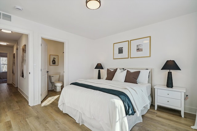 bedroom featuring connected bathroom and light hardwood / wood-style flooring