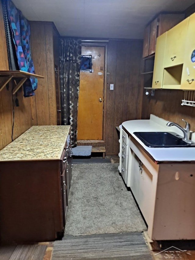 kitchen featuring wooden walls, light countertops, a sink, and a center island