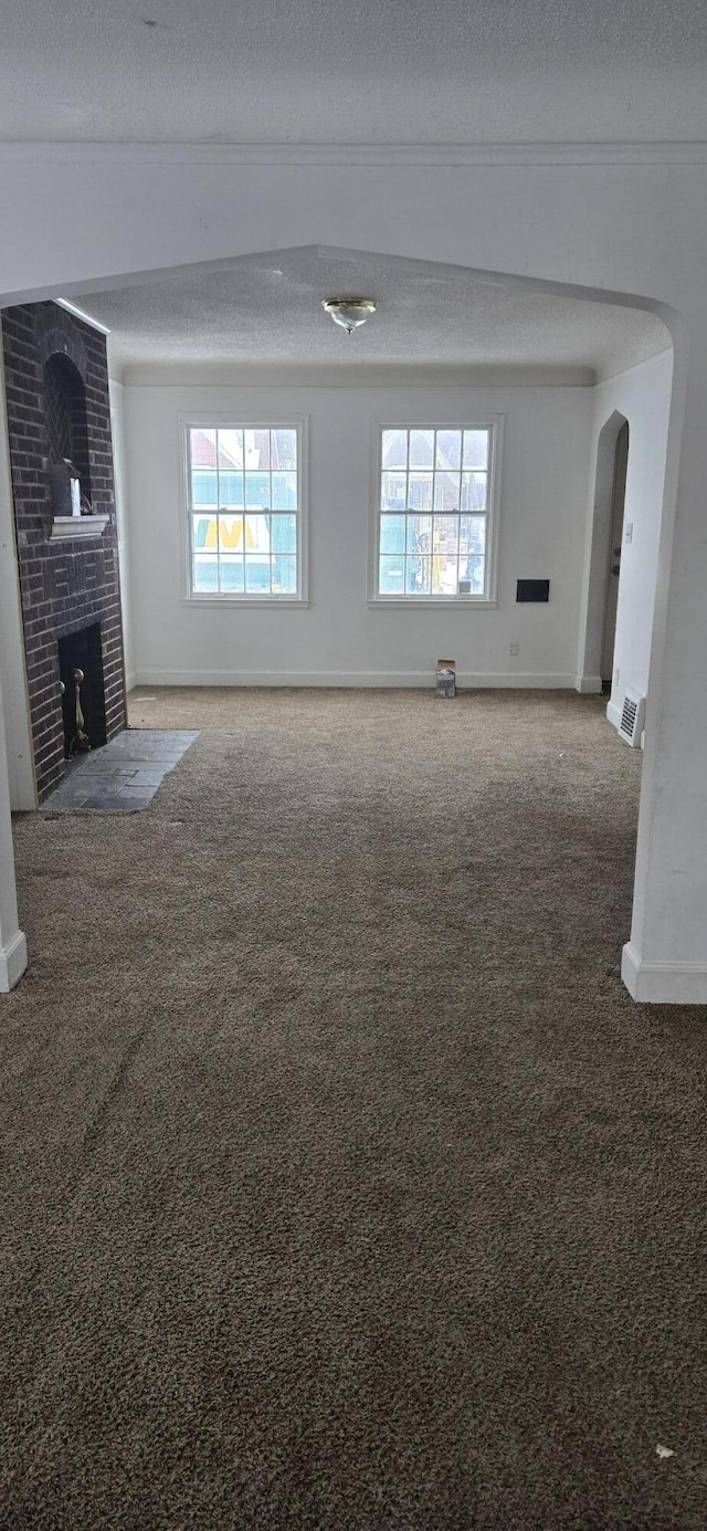 unfurnished living room featuring carpet flooring, a fireplace, and a textured ceiling